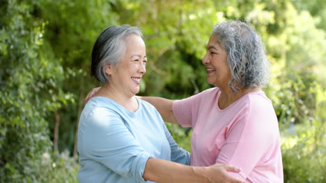 Senior-biracial-woman-and-Asian-woman-embrace-outdoors