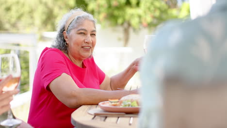 Senior-biracial-woman-enjoys-a-meal-outdoors,-with-copy-space