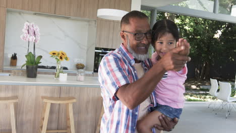 Biracial-grandfather-and-his-granddaughter-share-a-joyful-moment-in-a-modern-kitchen