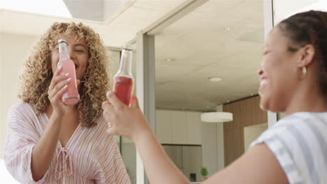 Biracial-women-share-a-cheerful-moment-with-drinks