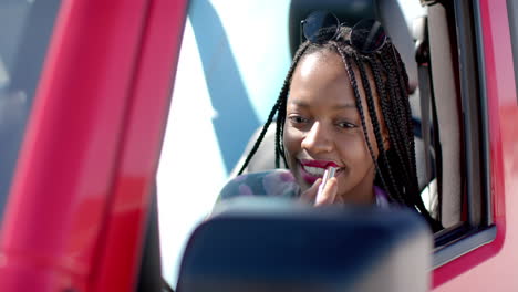 Young-African-American-woman-applies-lipstick-in-the-car-on-a-road-trip-with-copy-space