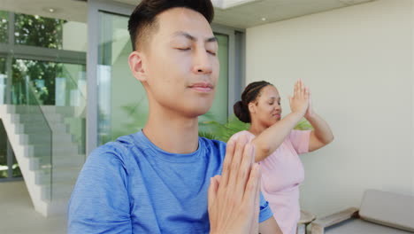 Young-Asian-man-and-young-Biracial-woman-practice-yoga-outdoors