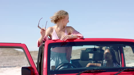Young-Caucasian-woman-stands-by-a-red-vehicle-outdoors-on-a-road-trip