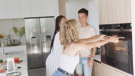 Young-Asian-man-and-biracial-women-share-a-high-five-in-a-modern-kitchen