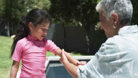 Biracial-girl-with-long-black-hair-in-a-pink-top-receives-something-from-her-grandmother