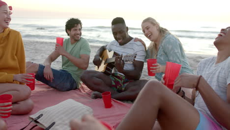 Diverse-friends-enjoy-a-beach-gathering-at-sunset