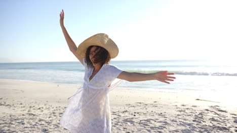 Young-biracial-woman-enjoys-the-beach-with-copy-space,-arms-outstretched-towards-the-sea