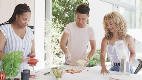 Young-Asian-man-and-biracial-women-enjoy-cooking-together-at-home,-making-pizza