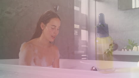 Animation-of-dropper-bottle-of-essential-oil-over-caucasian-woman-in-bath-splashing-face