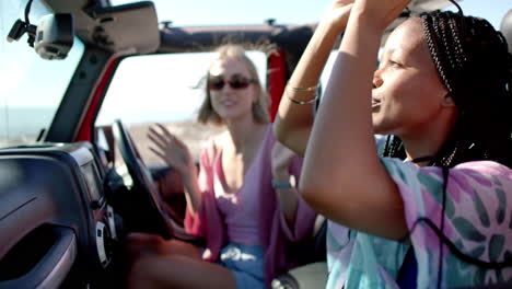 Young-African-American-woman-and-young-Caucasian-woman-enjoy-a-conversation-in-a-car-on-a-road-trip