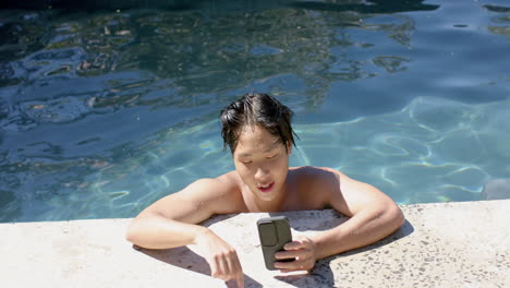Teenage-Asian-boy-enjoys-a-sunny-day-by-the-pool,-with-copy-space