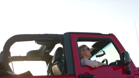 Young-Caucasian-woman-enjoys-a-drive-in-a-red-convertible-on-a-road-trip-with-copy-space