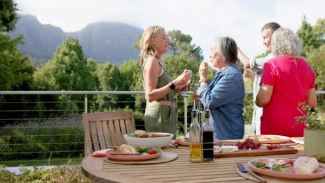 Diverse-group-of-women-enjoy-a-meal-outdoors,-with-a-mountainous-backdrop