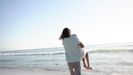Biracial-couple-enjoys-a-playful-moment-on-a-sunny-beach