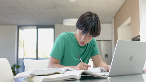 Asiatischer-Teenager-Studiert-Intensiv-An-Seinem-Laptop-An-Einem-Tisch