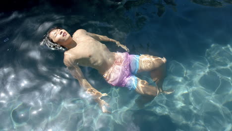 Teenage-Asian-boy-floats-peacefully-in-clear-pool-water