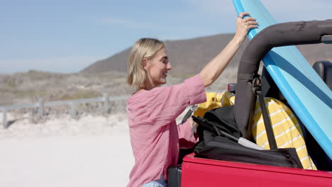 A-young-Caucasian-woman-packs-a-car-for-a-beach-trip-on-a-road-trip-with-copy-space