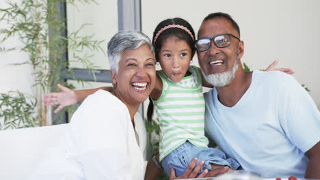 Biracial-couple-with-their-granddaughter-are-smiling-at-the-camera