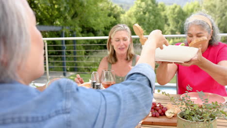 Senior-Caucasian-and-biracial-women-enjoy-a-meal-outdoors
