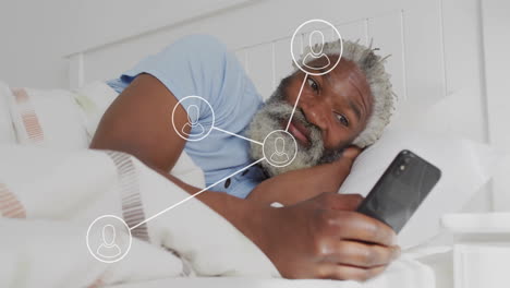 Animation-of-network-of-connections-with-icons-over-senior-african-american-man-using-smartphone