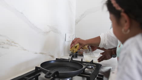 A-biracial-man-pours-oil-into-a-frying-pan,-preparing-to-cook