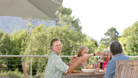 Diverse-group-of-women-enjoy-a-meal-outdoors,-with-copy-space