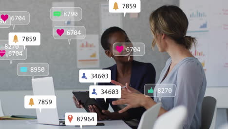 Animation-of-social-media-icons-with-numbers-over-diverse-colleagues-discussing-work-in-office