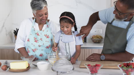 A-biracial-girl-is-baking-with-her-grandparents-in-a-modern-kitchen