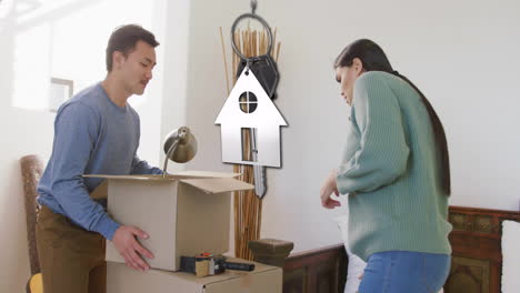 Animation-of-silver-house-key-and-key-fob-over-happy-diverse-couple-moving-in-to-new-home