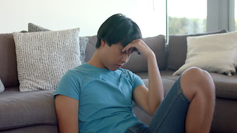 Asiatischer-Teenager-Sieht-Gestresst-Aus,-Als-Würde-Er-Zu-Hause-Auf-Der-Couch-Sitzen