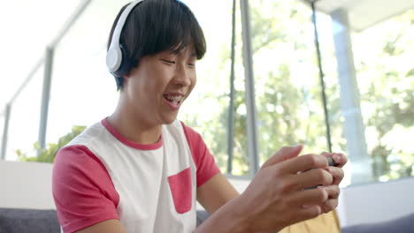 Teenage-Asian-boy-enjoys-gaming-on-smartphone-at-home