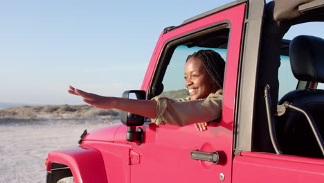 Young-African-American-woman-enjoys-a-sunny-day-in-a-vibrant-pink-jeep-on-a-road-trip