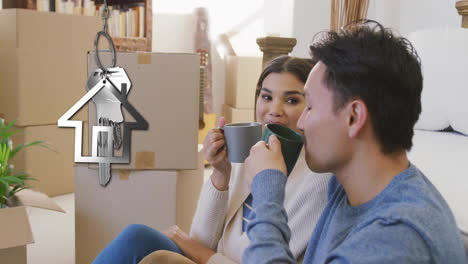 Animation-of-silver-house-key-and-key-fob-over-diverse-couple-drinking-tea-at-new-home
