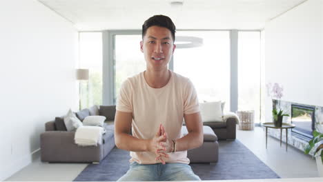 Der-Junge-Asiatische-Mann-Sitzt-Lässig-In-Einem-Modernen-Wohnzimmer-Und-Telefoniert-Mit-Einem-Video