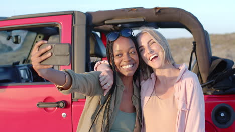 Young-African-American-woman-and-young-Caucasian-woman-take-a-selfie-outdoors-on-a-road-trip