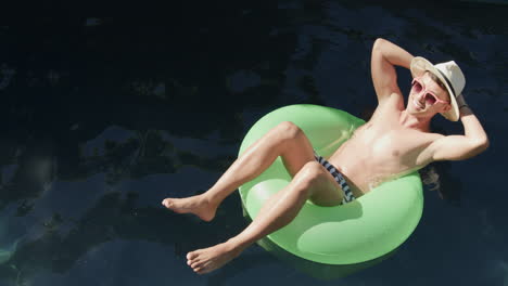 Young-Asian-man-enjoys-a-relaxing-day-floating-in-a-pool,-with-copy-space
