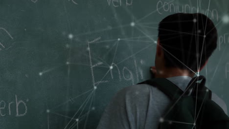 Animation-of-network-of-connections-over-biracial-schoolboy-writing-on-chalkboard
