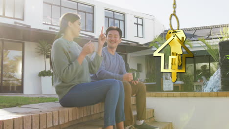 Animation-of-gold-house-key-and-key-fob-over-happy-diverse-couple-by-house