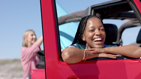 Young-African-American-woman-leans-on-a-car-door-on-a-road-trip