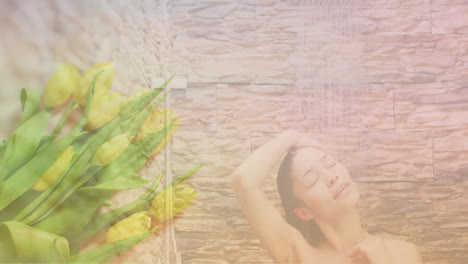 Animation-of-yellow-flowers-over-happy-biracial-woman-washing-in-shower