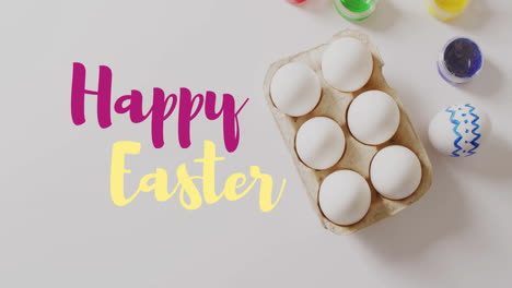 Animation-of-happy-easter-text-over-easter-eggs-and-paints-on-white-background