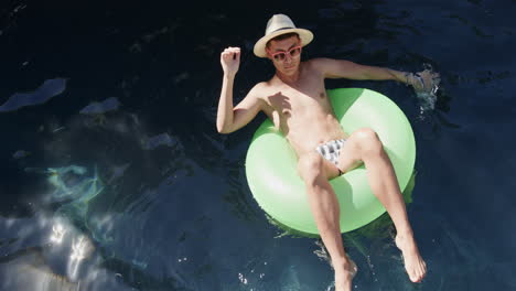 Young-man-enjoys-a-relaxing-day-floating-in-a-pool,-with-copy-space