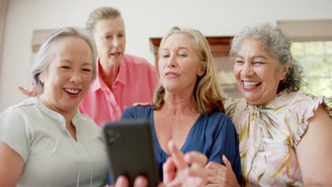 Senior-diverse-group-of-women-laughing-and-looking-at-a-smartphone