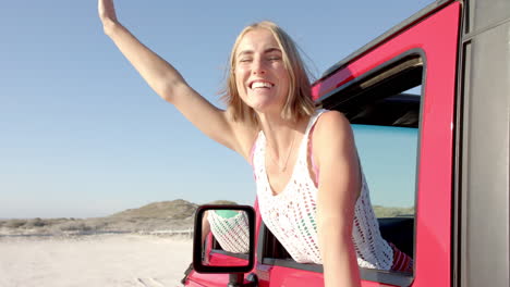Young-Caucasian-woman-enjoys-a-sunny-day-at-the-beach-from-her-car-on-a-road-trip