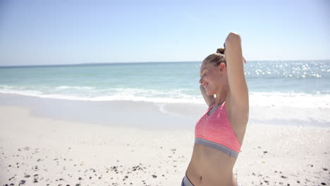 A-young-Caucasian-woman-is-stretching-on-a-sunny-beach-with-copy-space
