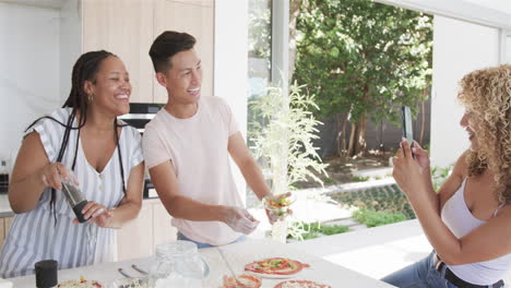 Young-Asian-man-and-biracial-women-enjoy-cooking-together-at-home,-making-pizza