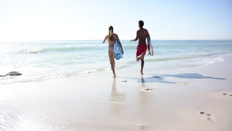 Young-Caucasian-woman-and-biracial-man-are-running-along-the-beach-with-copy-space