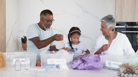 Biracial-family-engaged-in-recycling,-with-a-granddaughter-learning-to-sort-materials