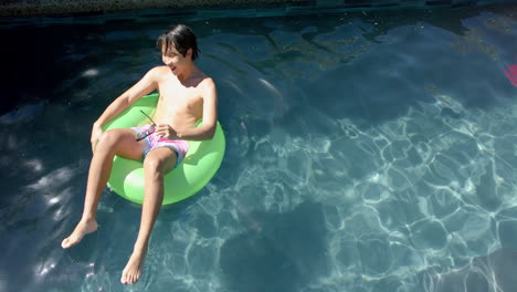 Teenage-Asian-boy-enjoys-a-sunny-day-in-the-pool,-with-copy-space