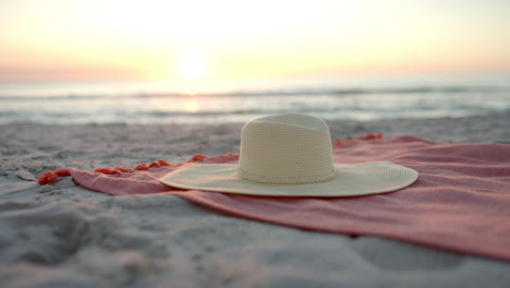 A-diverse-sun-hat-rests-on-a-beach-towel-at-sunset,-with-copy-space